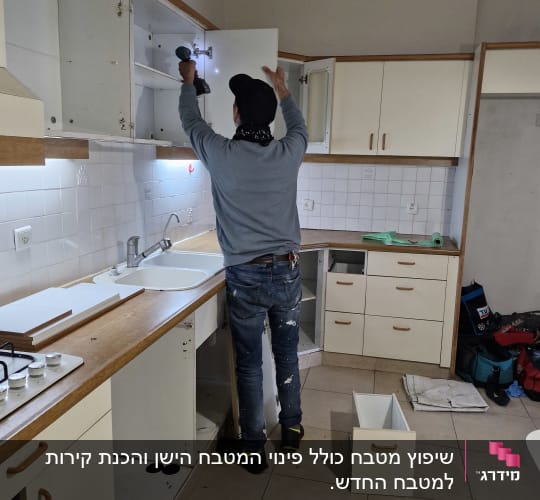 אדם מתקין דלת ארון במטבח עם מברגה חשמלית